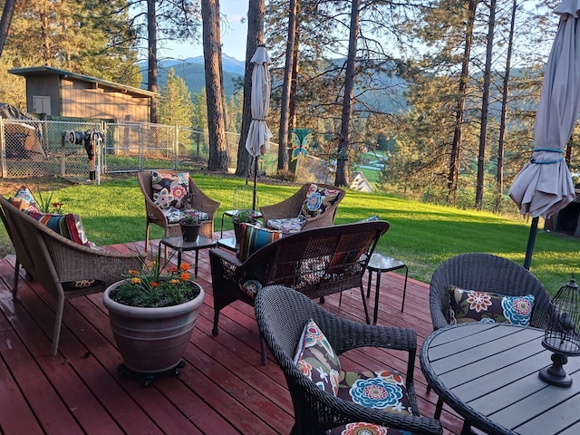 wooden deck with an outdoor hangout area, a lawn, fence, and a mountain view