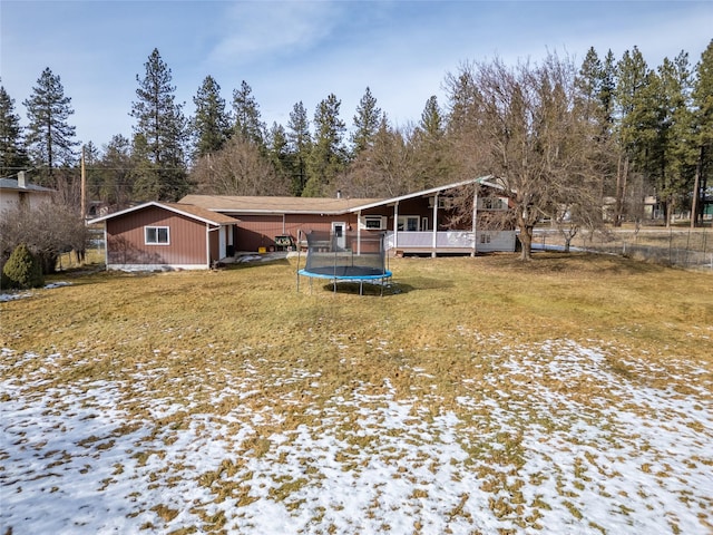 snow covered property featuring a yard and a trampoline