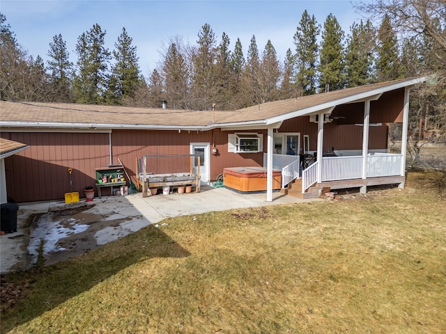 back of house with a yard, a porch, a ceiling fan, and a hot tub