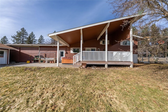 back of house featuring a patio area, a lawn, and a hot tub