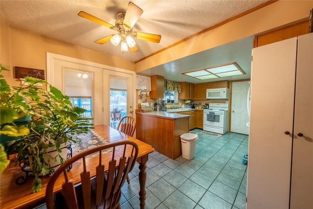 kitchen with light countertops, a sink, a textured ceiling, white appliances, and a peninsula