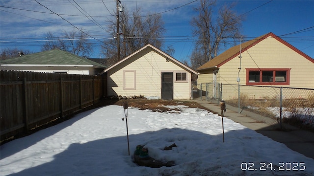 snow covered rear of property with a fenced backyard