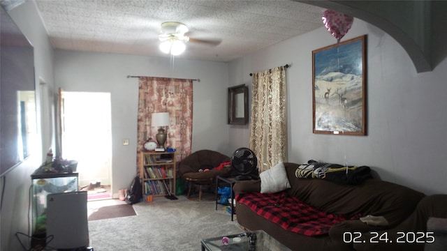 living room featuring carpet floors, arched walkways, a textured ceiling, and a ceiling fan