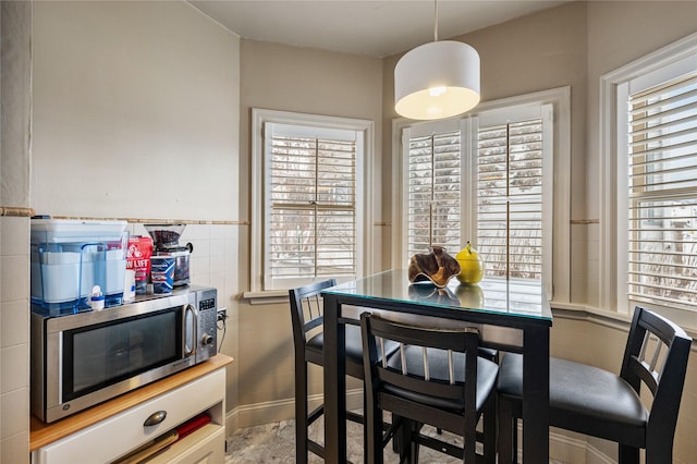 dining space with a wainscoted wall and tile walls