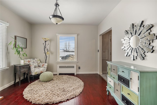 sitting room featuring dark wood-style flooring, baseboards, and radiator heating unit