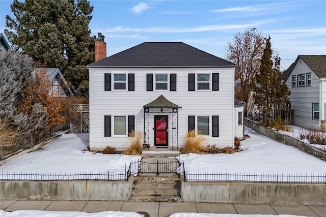 colonial house featuring a fenced front yard and a chimney