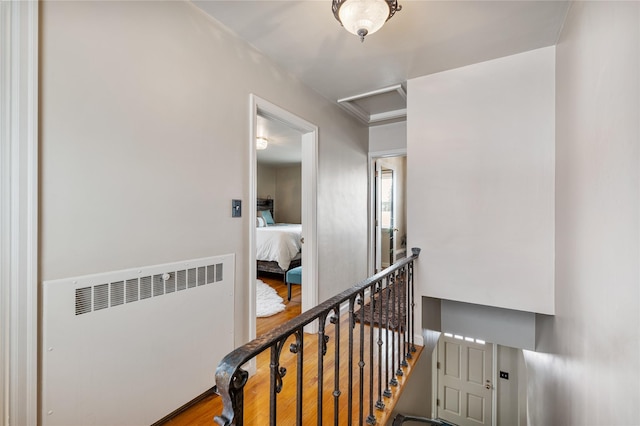 hallway featuring radiator, attic access, wood finished floors, and an upstairs landing