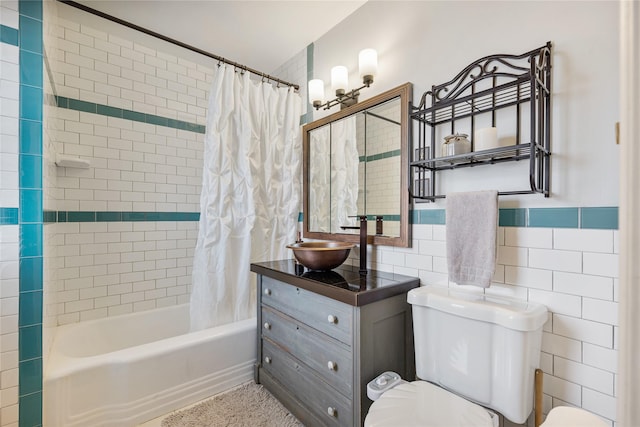 full bath with shower / tub combo with curtain, tile walls, toilet, and vanity