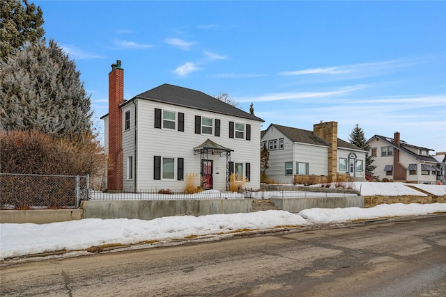 colonial-style house with a fenced front yard and a chimney