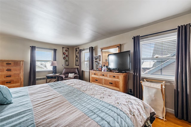 bedroom featuring radiator, light wood-type flooring, and baseboards