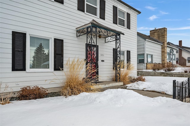 snow covered property entrance featuring fence