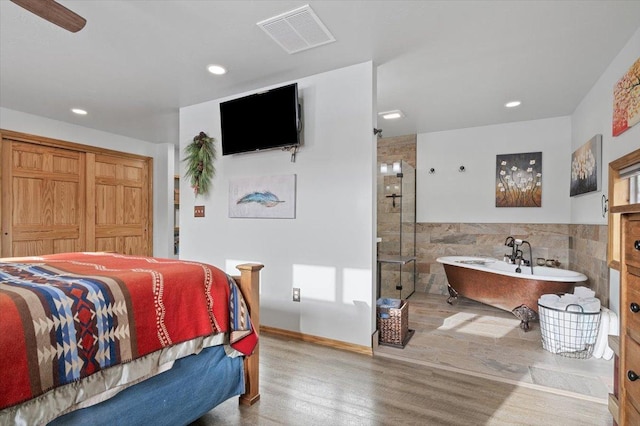 bedroom featuring recessed lighting, a wainscoted wall, wood finished floors, visible vents, and tile walls