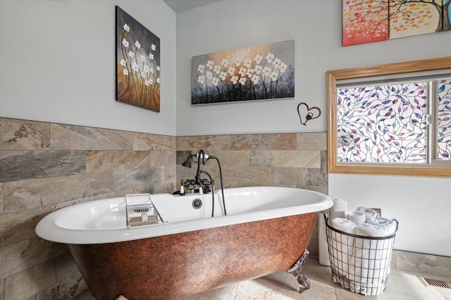 full bathroom with visible vents, tile walls, a freestanding bath, and wainscoting