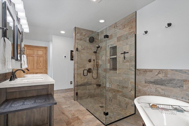 bathroom with tile walls, double vanity, a stall shower, a sink, and a freestanding tub