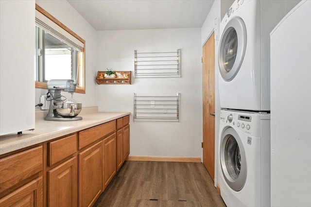 washroom with stacked washing maching and dryer, baseboards, laundry area, and dark wood finished floors