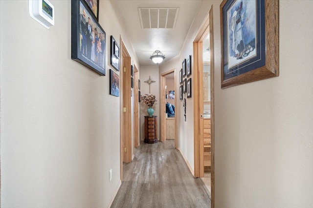 hallway featuring visible vents and wood finished floors