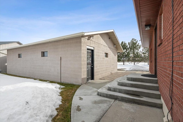 view of snowy exterior featuring concrete block siding