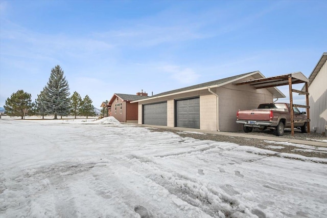 snow covered garage with a garage and a carport