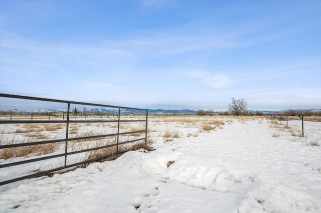 yard layered in snow with a rural view and fence