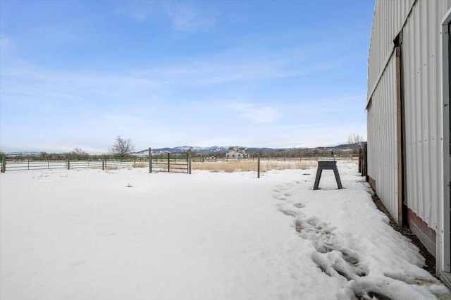 yard covered in snow featuring fence and a mountain view