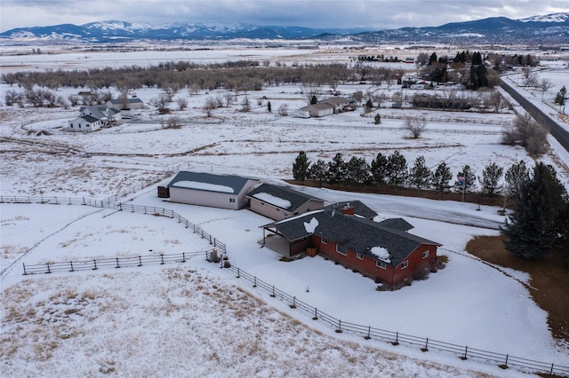 snowy aerial view with a rural view and a mountain view