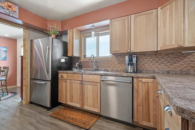 kitchen with backsplash, stainless steel appliances, a sink, and light brown cabinetry