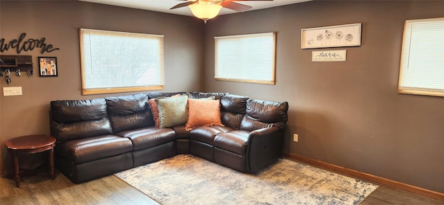 living area with a ceiling fan, baseboards, and wood finished floors