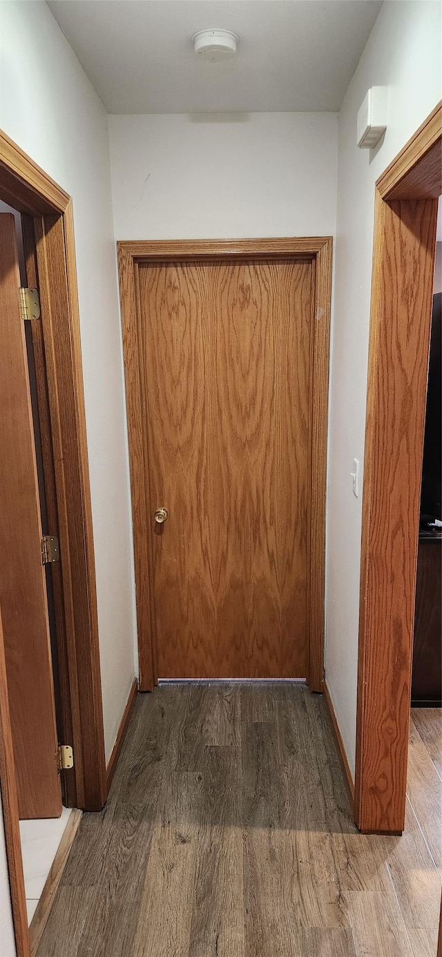 corridor with baseboards and wood finished floors