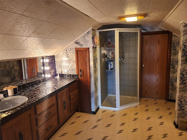 full bath featuring lofted ceiling, a sink, a shower stall, tile patterned floors, and double vanity