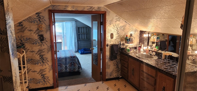 bathroom featuring lofted ceiling, tile patterned floors, vanity, and wallpapered walls