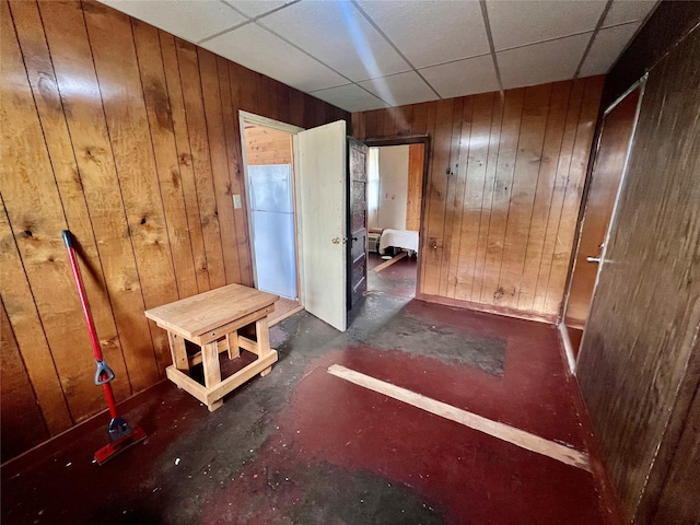 interior space with a paneled ceiling and wooden walls