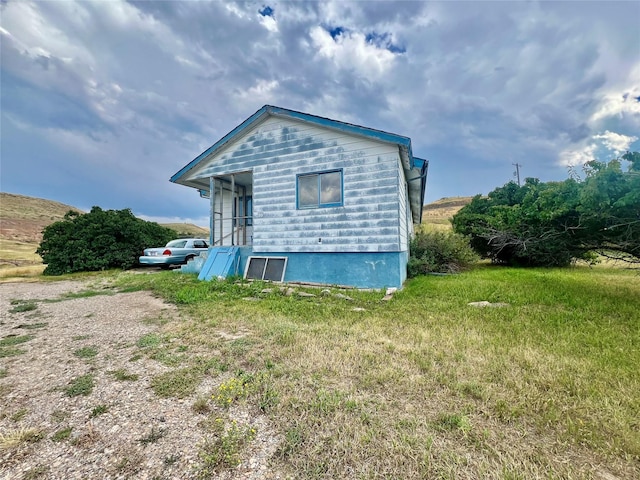 back of property with driveway and a lawn