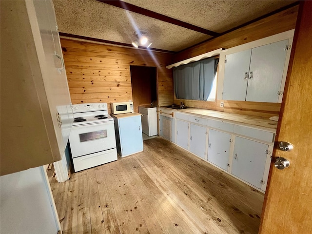 kitchen featuring a textured ceiling, light countertops, white appliances, and light wood-type flooring