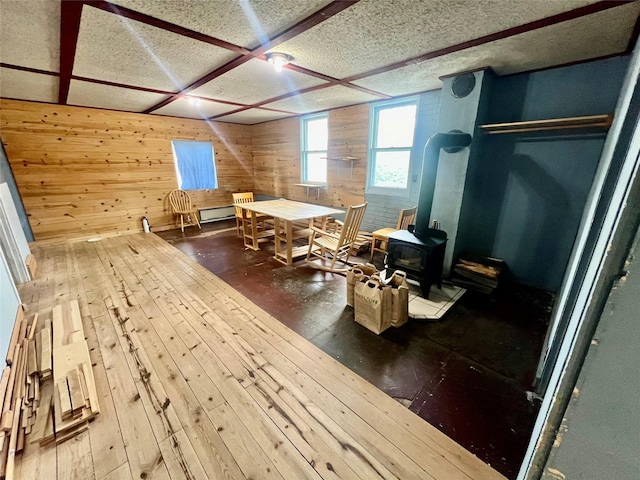 interior space with a wood stove, wood walls, coffered ceiling, and a textured ceiling