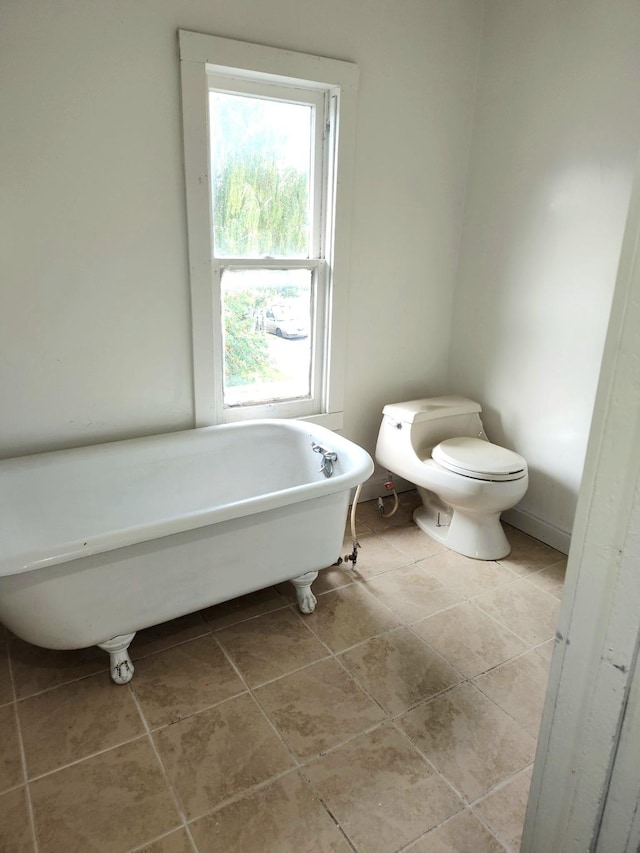 full bathroom featuring a freestanding bath, toilet, and tile patterned floors