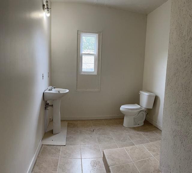 bathroom featuring a sink, toilet, and baseboards