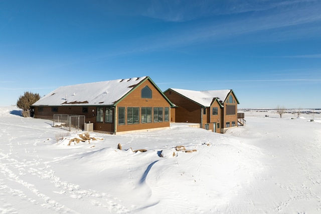 snow covered rear of property with a sunroom