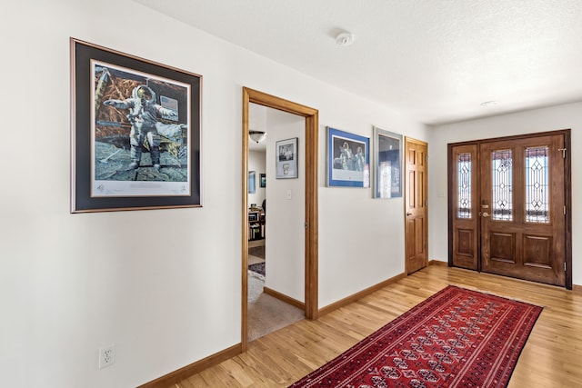 foyer with a textured ceiling, baseboards, and wood finished floors