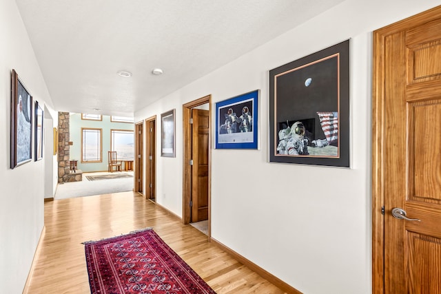 hall with light wood-style floors and baseboards