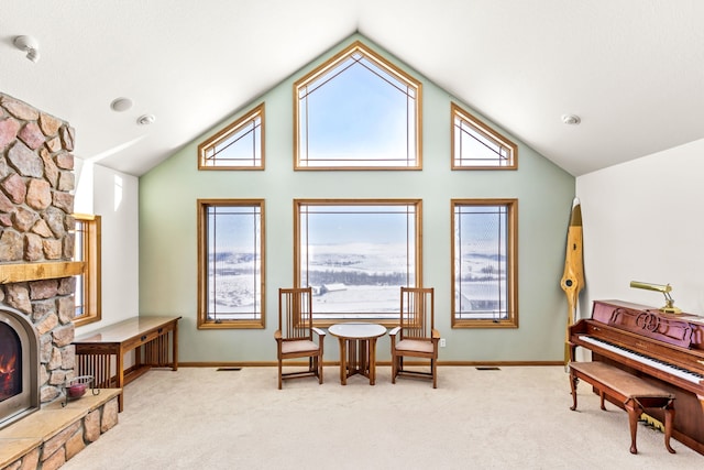 living area featuring a healthy amount of sunlight, light colored carpet, and a stone fireplace