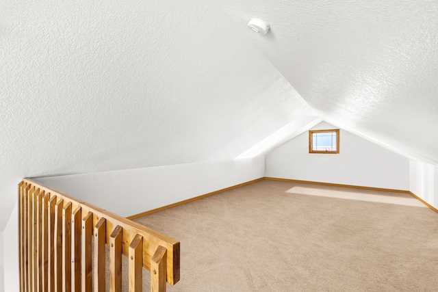 bonus room with carpet, vaulted ceiling, a textured ceiling, and baseboards