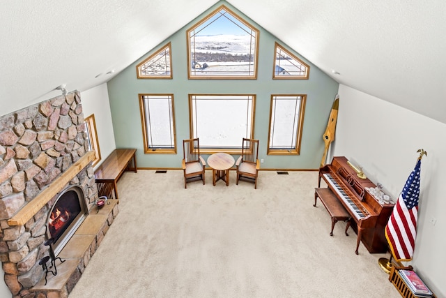 sitting room featuring lofted ceiling, a stone fireplace, light colored carpet, and a textured ceiling