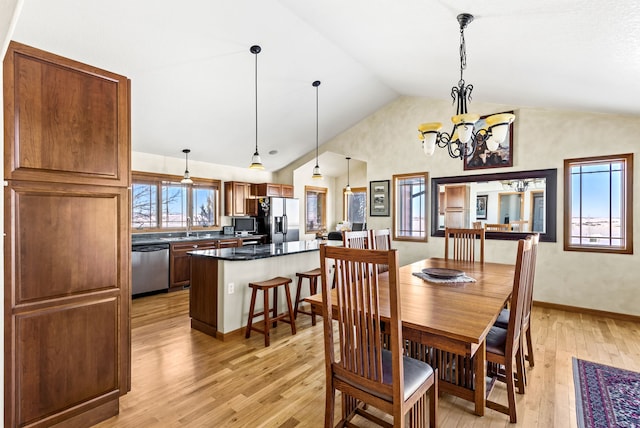 dining room with a chandelier, high vaulted ceiling, light wood-style flooring, and baseboards