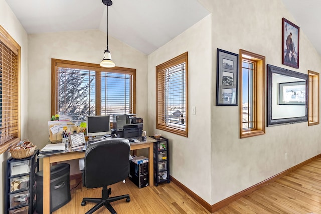 office space with light wood-style floors, vaulted ceiling, and baseboards