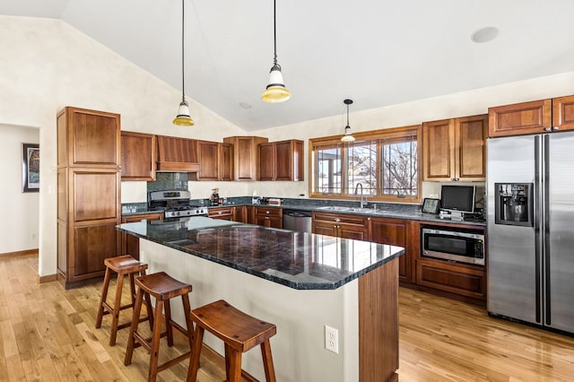 kitchen with a sink, hanging light fixtures, appliances with stainless steel finishes, and a kitchen island