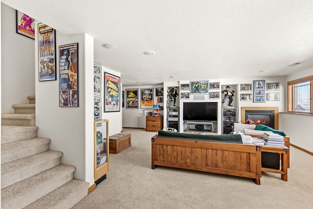 living area with visible vents, stairway, light colored carpet, and a glass covered fireplace