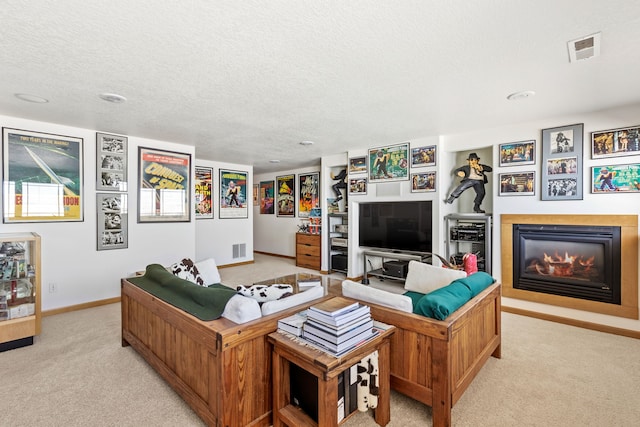 living room with a glass covered fireplace, visible vents, light carpet, and a textured ceiling