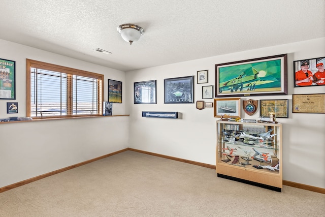 unfurnished room with light colored carpet, a textured ceiling, and baseboards