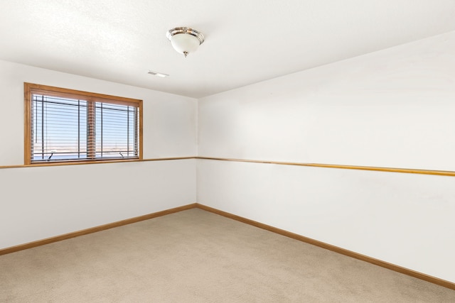 empty room featuring carpet flooring, visible vents, and baseboards