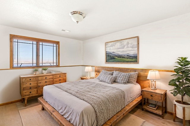 bedroom featuring light wood-style floors, baseboards, and visible vents